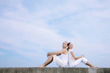 Erkek ve kadın sırt sırta oturuyor.