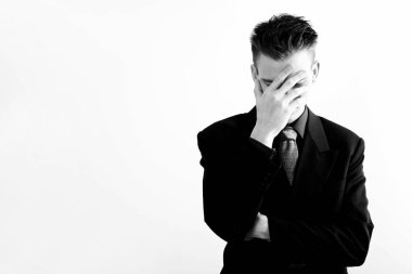 İş adamı elleriyle yüzünü kapatıyor.