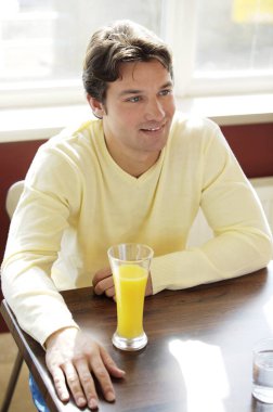 Kafede bir bardak meyve suyu içen bir adam