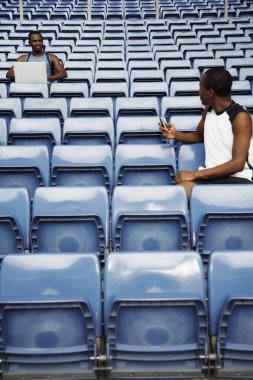 Cep telefonlu bir adam laptoplu bir adamla konuşuyor.