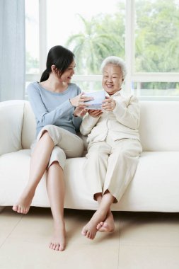 Yaşlı bir kadına hediye paketi veren bir kadın.