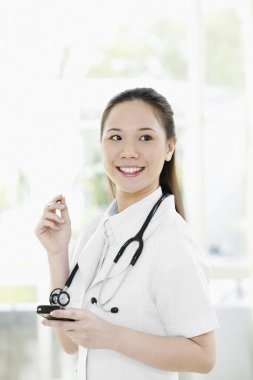 Avuç içi bilgisayarı tutarken gülümseyen kadın doktor