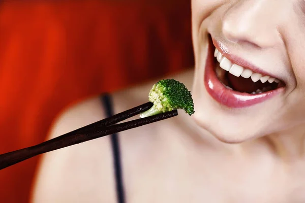 Woman about to eat broccoli