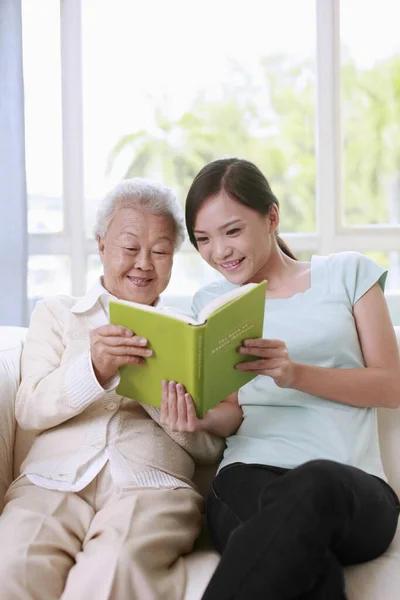 Ηλικιωμένη Γυναίκα Και Γυναίκα Διαβάζουν Μαζί Βιβλίο — Φωτογραφία Αρχείου