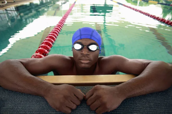 Man in swimming pool, hanging onto edge