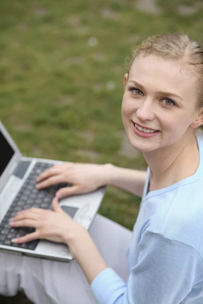 Kobieta Uśmiechnięta Kamery Podczas Korzystania Laptopa — Zdjęcie stockowe