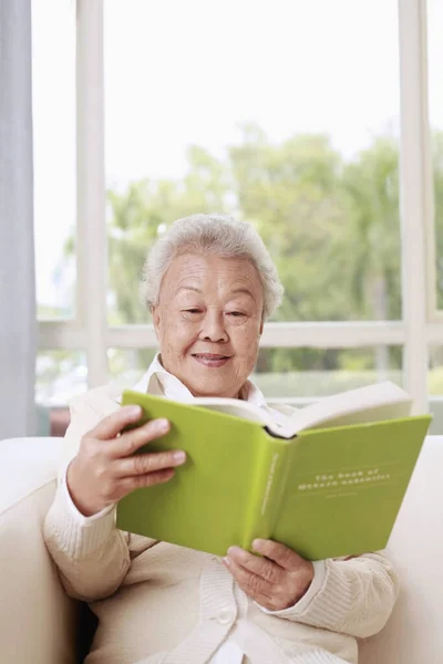 Senior Mulher Sentada Sofá Leitura Livro — Fotografia de Stock