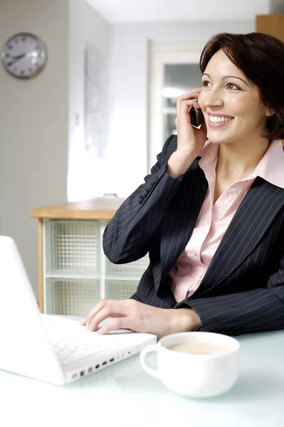 Bizneswoman Rozmawia Przez Telefon Podczas Korzystania Laptopa — Zdjęcie stockowe