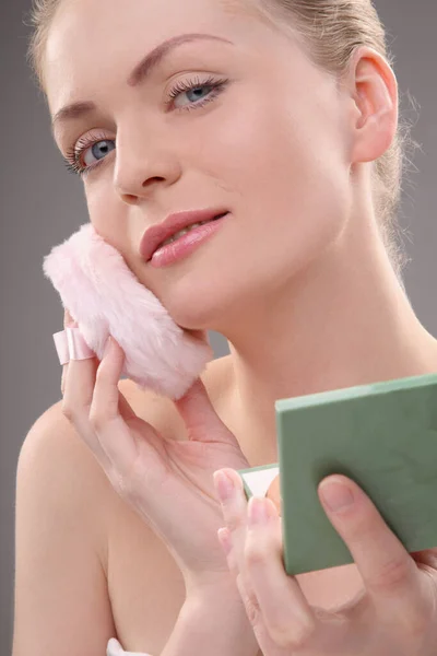 Woman applying powder with powder puff