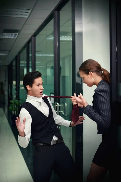 Businesswoman pulling businessman's necktie