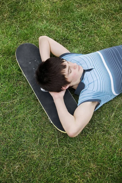 男孩把头靠在滑板上休息 — 图库照片