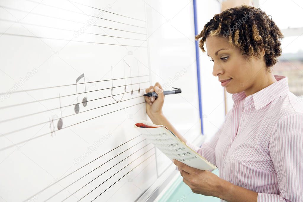 Woman writing music notes on the whiteboard