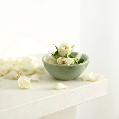 Kasenin yanına bir kase beyaz gül ve birkaç yaprak serpiştirilmiş.