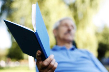 Elinde kitap tutan kıdemli bir adam.