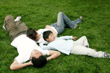 Ailesiyle birlikte çimenlerde yatan bir çocuk.