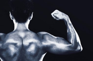 Adam kaslarını kasıyor, arkadan bakıyor.