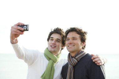 İki adam cep telefonuyla fotoğraf çekiyor.