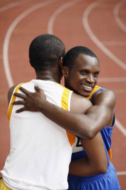 Erkekler yarıştan sonra birbirlerine sarılıyorlar.