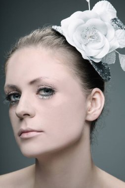 Çiçekli ve şapkalı bir kadın saçını dekore ediyor.