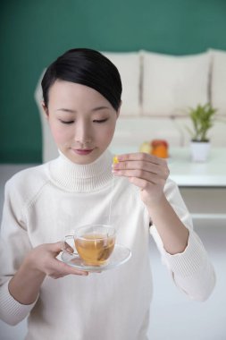 Kadın çay poşetini fincana daldırıyor.