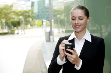 İş kadını telefonda mesajlaşırken gülümsüyor