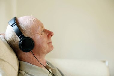 Son sınıf öğrencisi kanepede oturmuş kulaklıkla müzik dinliyor.