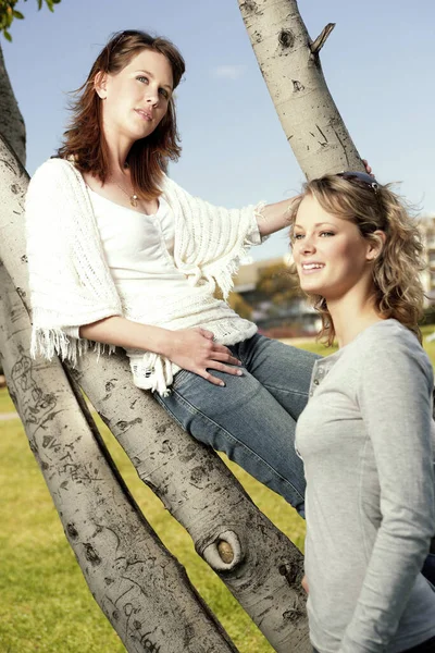 两个少女站在摄像机前的树枝旁边 — 图库照片