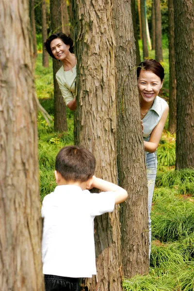 A boy playing hide and seek with his mother and grandmother