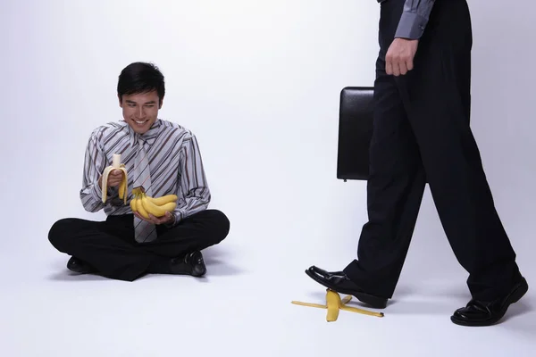 Zakenman Zit Vloer Banaan Eten Terwijl Een Andere Zakenman Bananenschil — Stockfoto