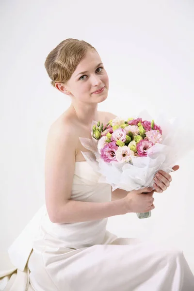 Woman in wedding gown holding a bouquet of flowers