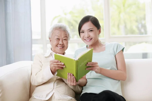 Ηλικιωμένη Γυναίκα Και Γυναίκα Διαβάζουν Μαζί Βιβλίο — Φωτογραφία Αρχείου