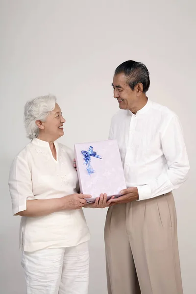 Senior woman receiving gift from senior man