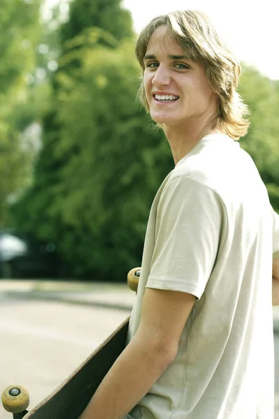 Εφηβικό Αγόρι Χαμογελά Κρατώντας Ένα Skateboard — Φωτογραφία Αρχείου