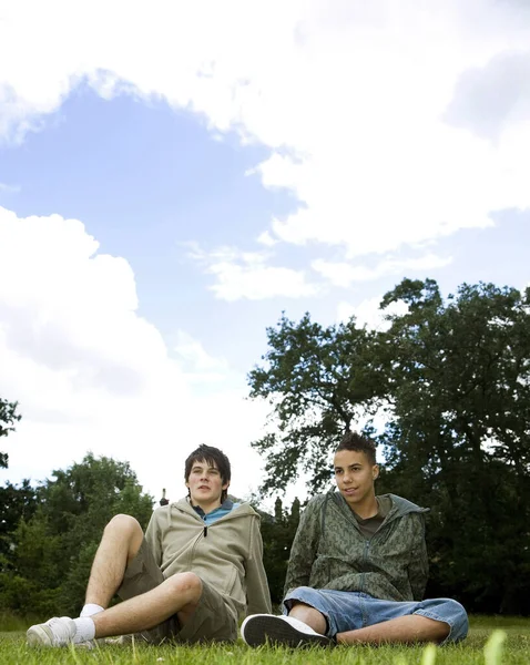 Αγόρια Κοιτάζουν Αλλού Ενώ Κάθονται Στο Γρασίδι — Φωτογραφία Αρχείου