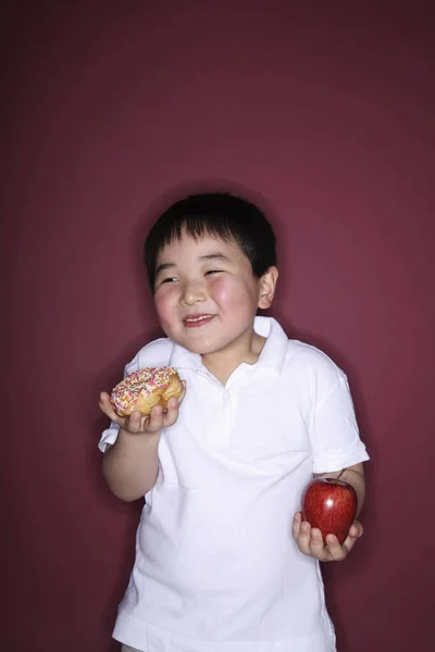 Chlapec Drží Koblihu Jablko Každé Ruce — Stock fotografie
