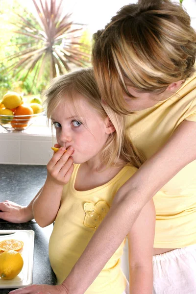 Uma Mulher Assistindo Sua Filha Comendo Limão — Fotografia de Stock