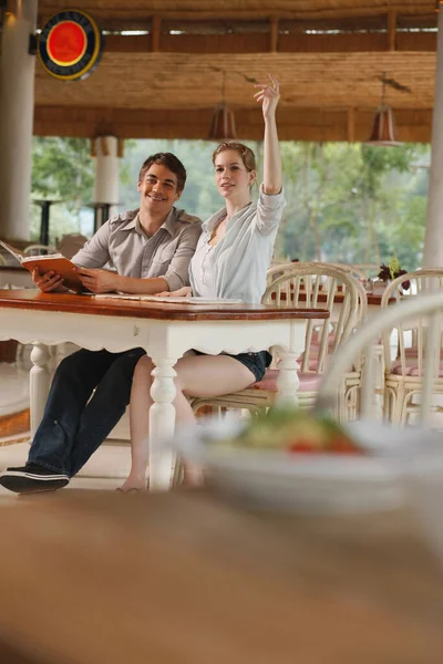 Man and woman in a restaurant, woman gesturing to order food