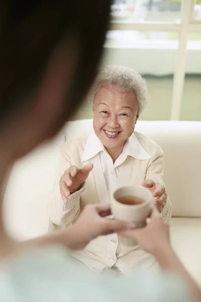 Yaşlı Kadına Bir Fincan Çayla Servis Yapan Kadın — Stok fotoğraf