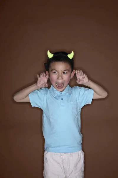 Boy wearing devil horns making hand gestures