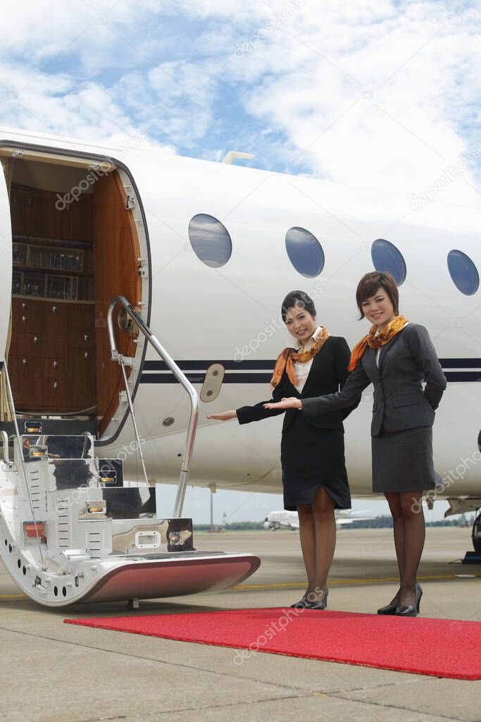 Flight attendants standing by private jet