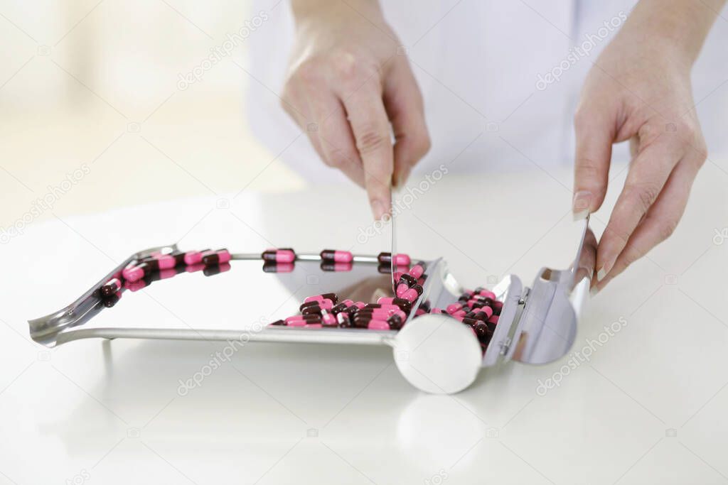 Doctor counting pills on pharmaceutical tray