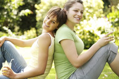 Kızlar parkta oturup içkilerini yudumluyorlar.
