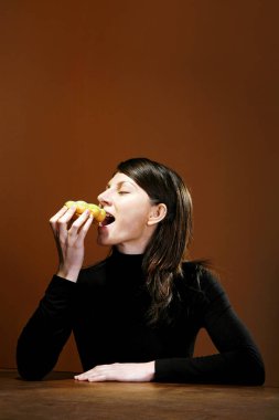 Genç bir kadın sandviç yiyor.