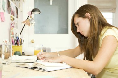 Odasında ödev yapan bir kız.