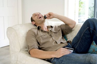 Kredi kartı tutan adam cep telefonuyla konuşuyor.