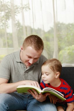 Erkek ve çocuk kitap okuyor.