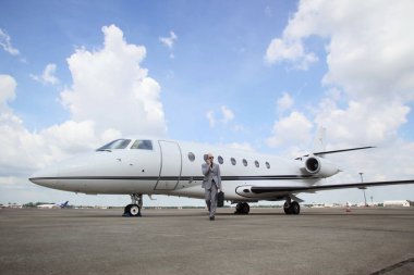 Arka planda özel jeti olan bir adam telefonda konuşuyor.