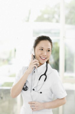 Kadın doktor telefonda konuşuyor.