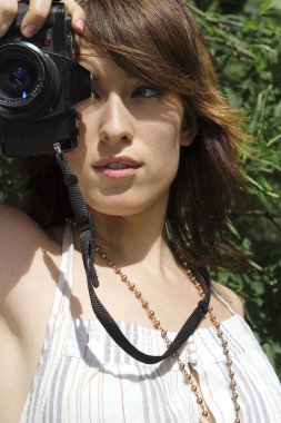 Kamerasıyla fotoğraf çeken bir kadın.