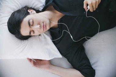Uyurken MP3 çalarda müzik dinleyen adam